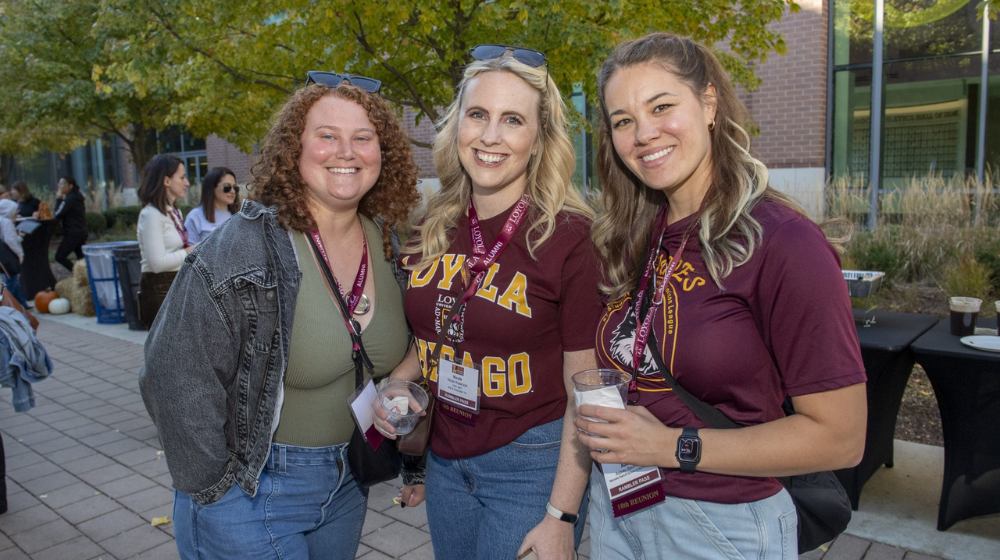 Three alumnae in Loyola University Chicago maroon tee shirts enjoy the festivities at Alumni Weekend 2024.